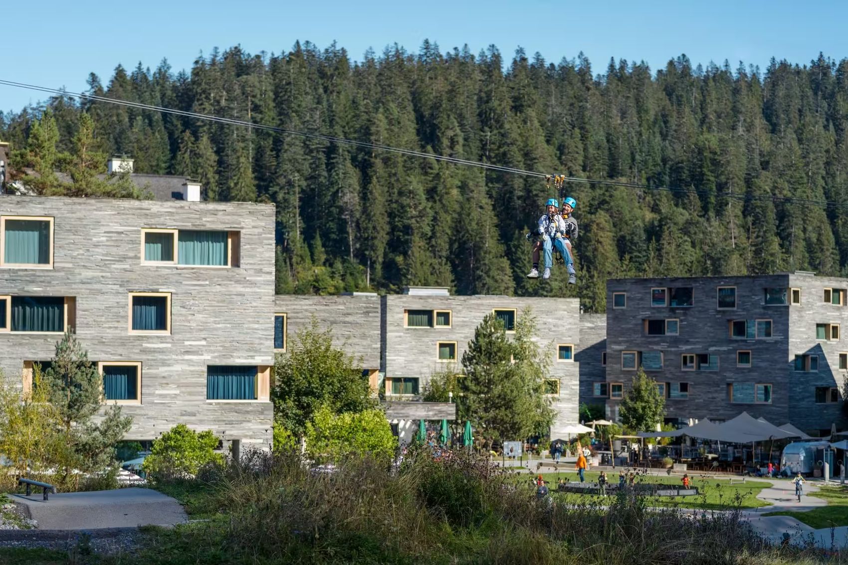 Father and child glide on the zipline over rocksresort