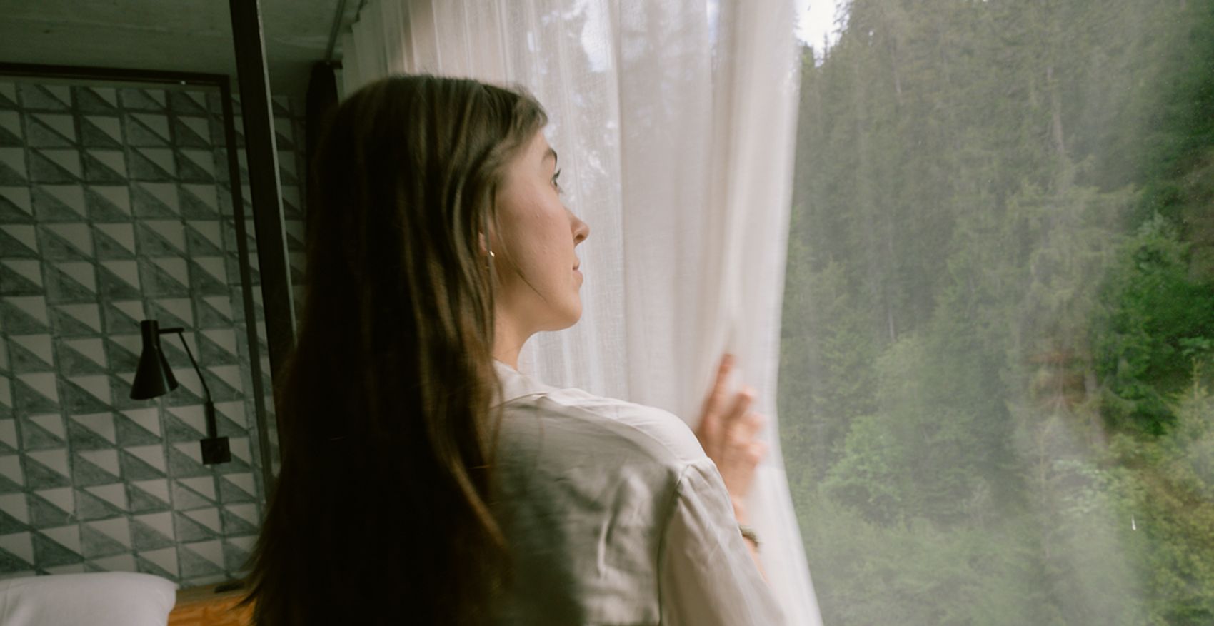 Frau schaut aus Zimmerfenster