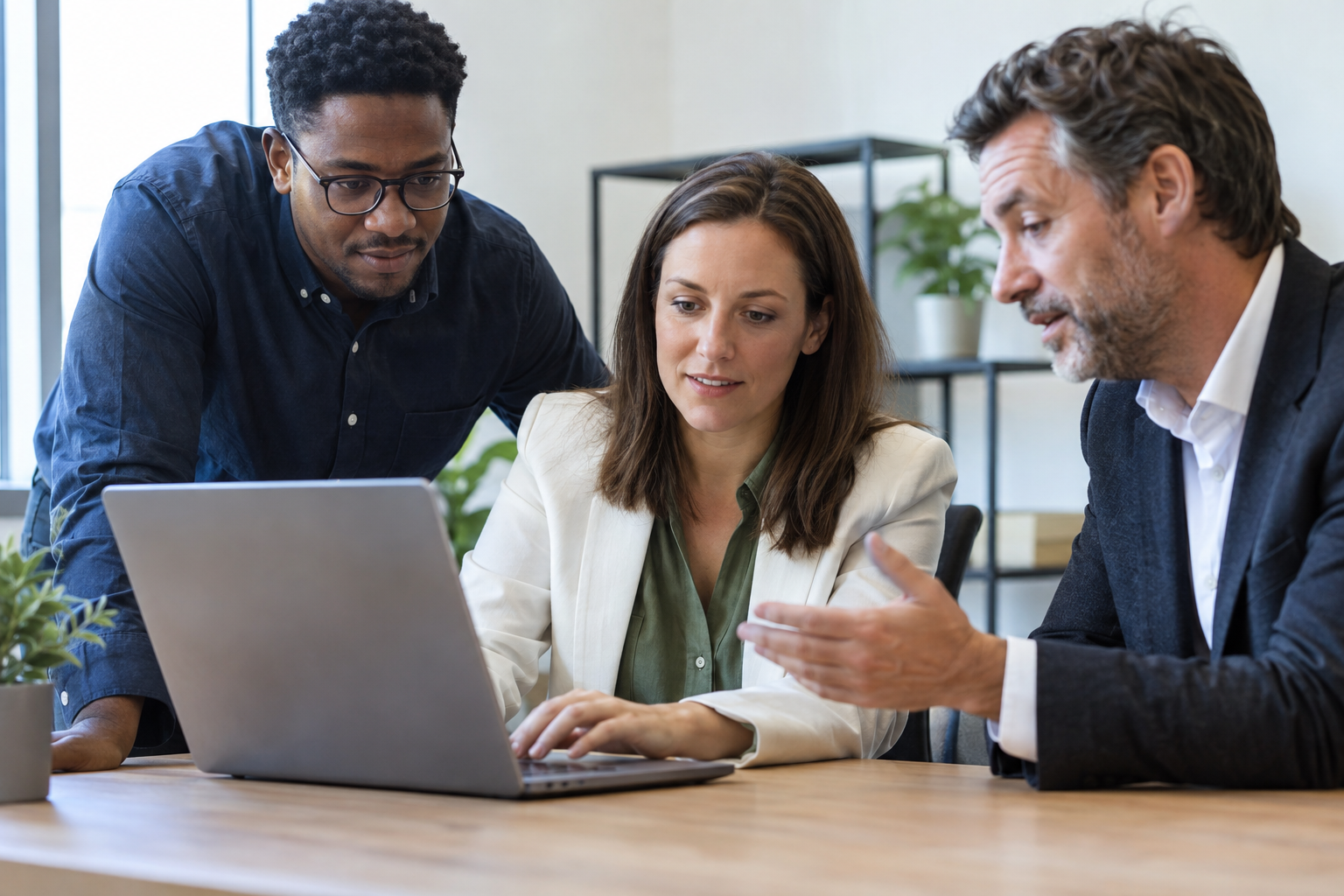 An HR manager tests software on a laptop with an IT colleague and business owner during a small-business buying evaluation.
