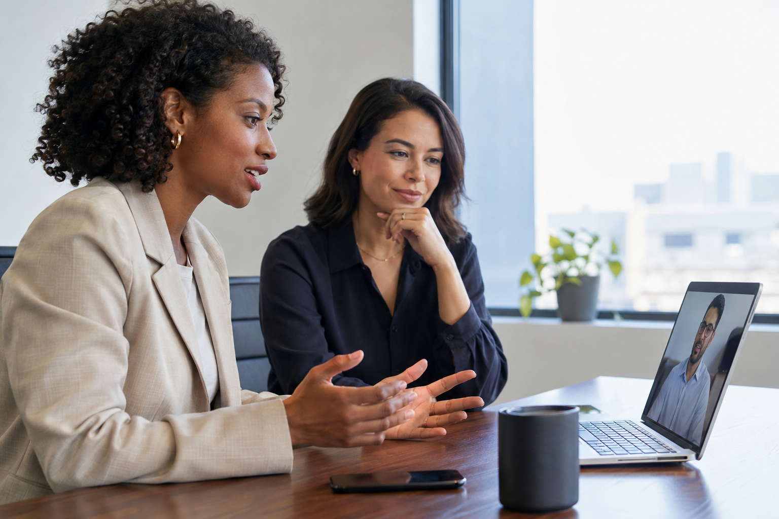 A hiring specialist conducts a laptop video interview while a recruiting colleague observes the screening pilot.