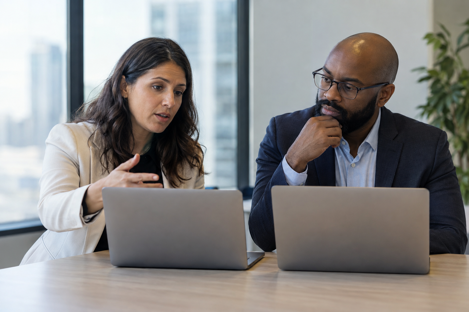 A finance lead and systems evaluator use laptops to test an ERP transaction exception and discuss escalation requirements.