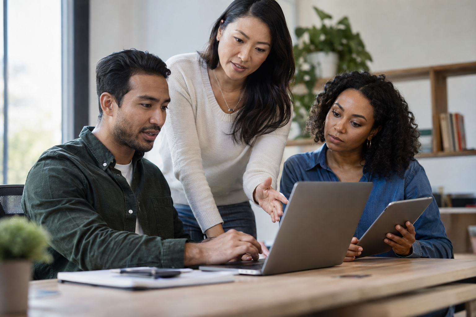 Small-business colleagues test an AI-assisted CRM handoff using a laptop and tablet while discussing setup effort.
