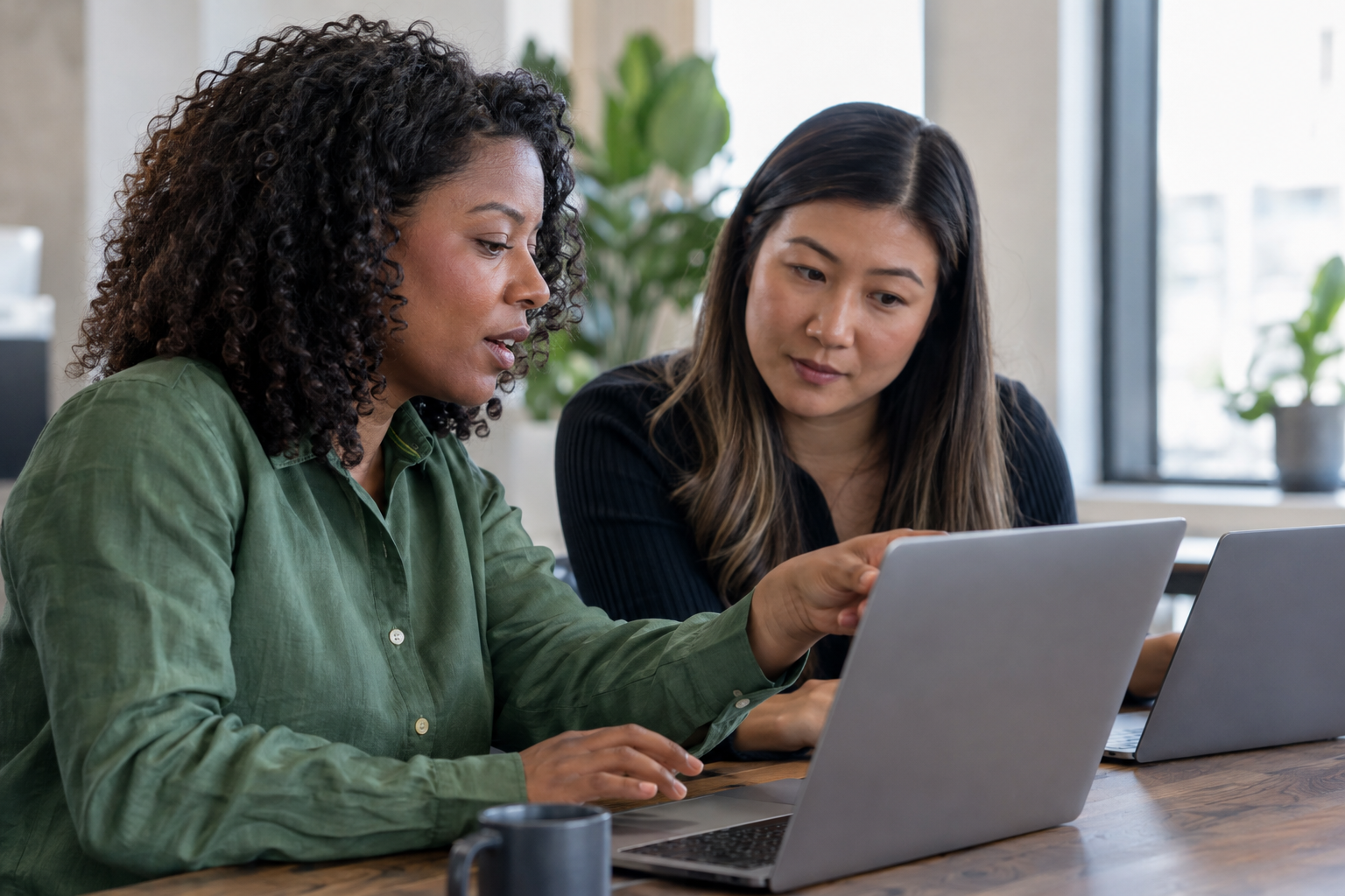 Two small-business colleagues use laptops to test an automated customer-inquiry handoff in a naturally lit workspace.