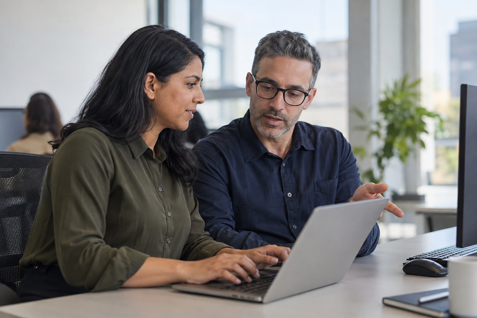 A finance approver and operations lead clarify ownership of a digital approval step while working together at a laptop.