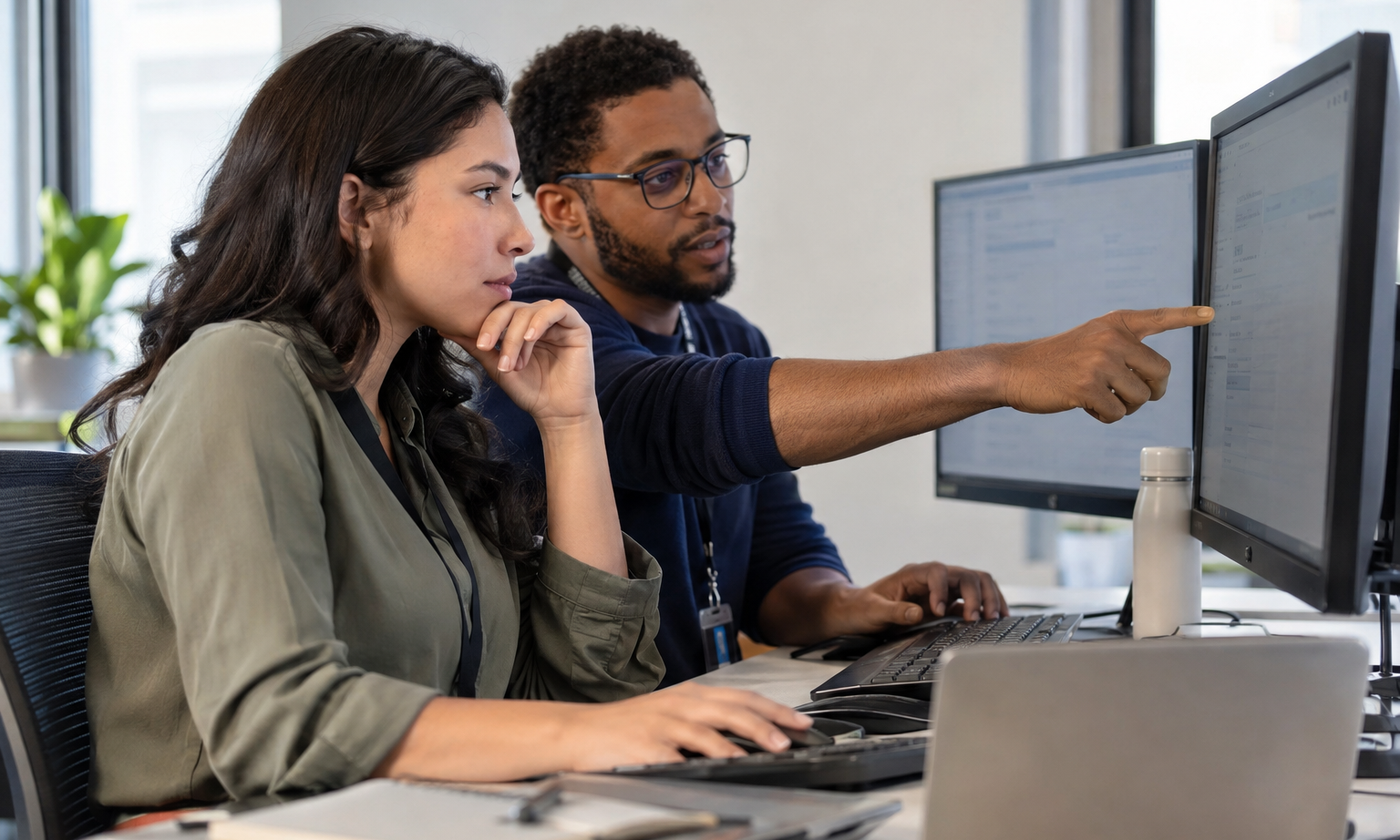 A quality analyst and operations specialist verify an AI agent’s completed back-office test case at desktop monitors.