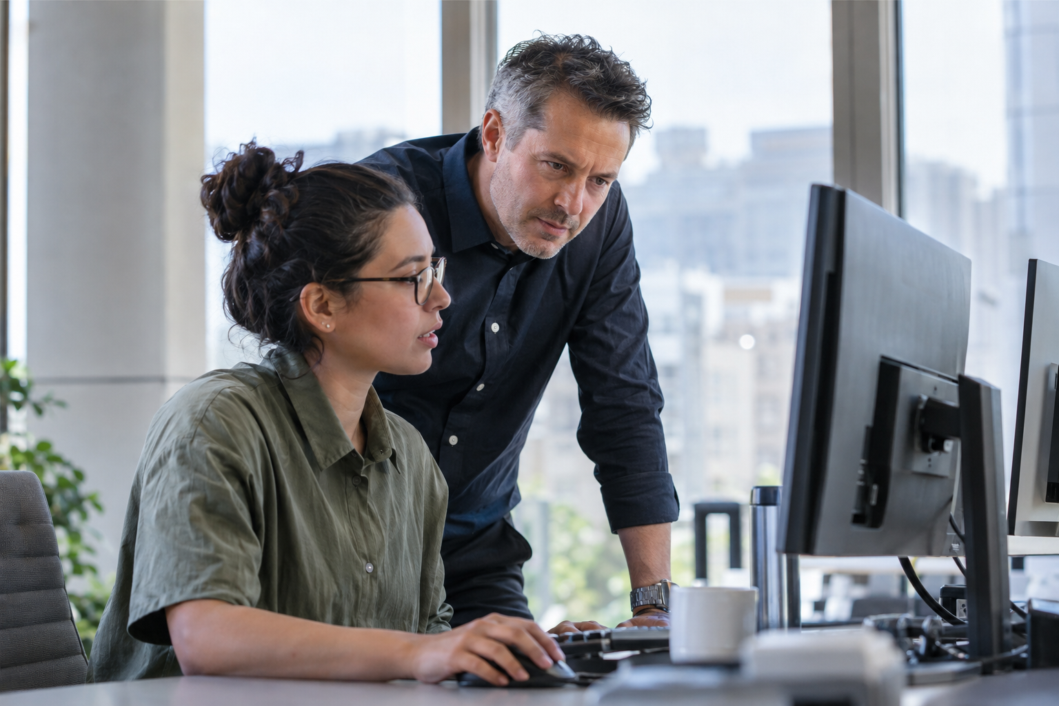 An operations specialist and senior colleague review a workflow failure at a computer before authorizing recovery.
