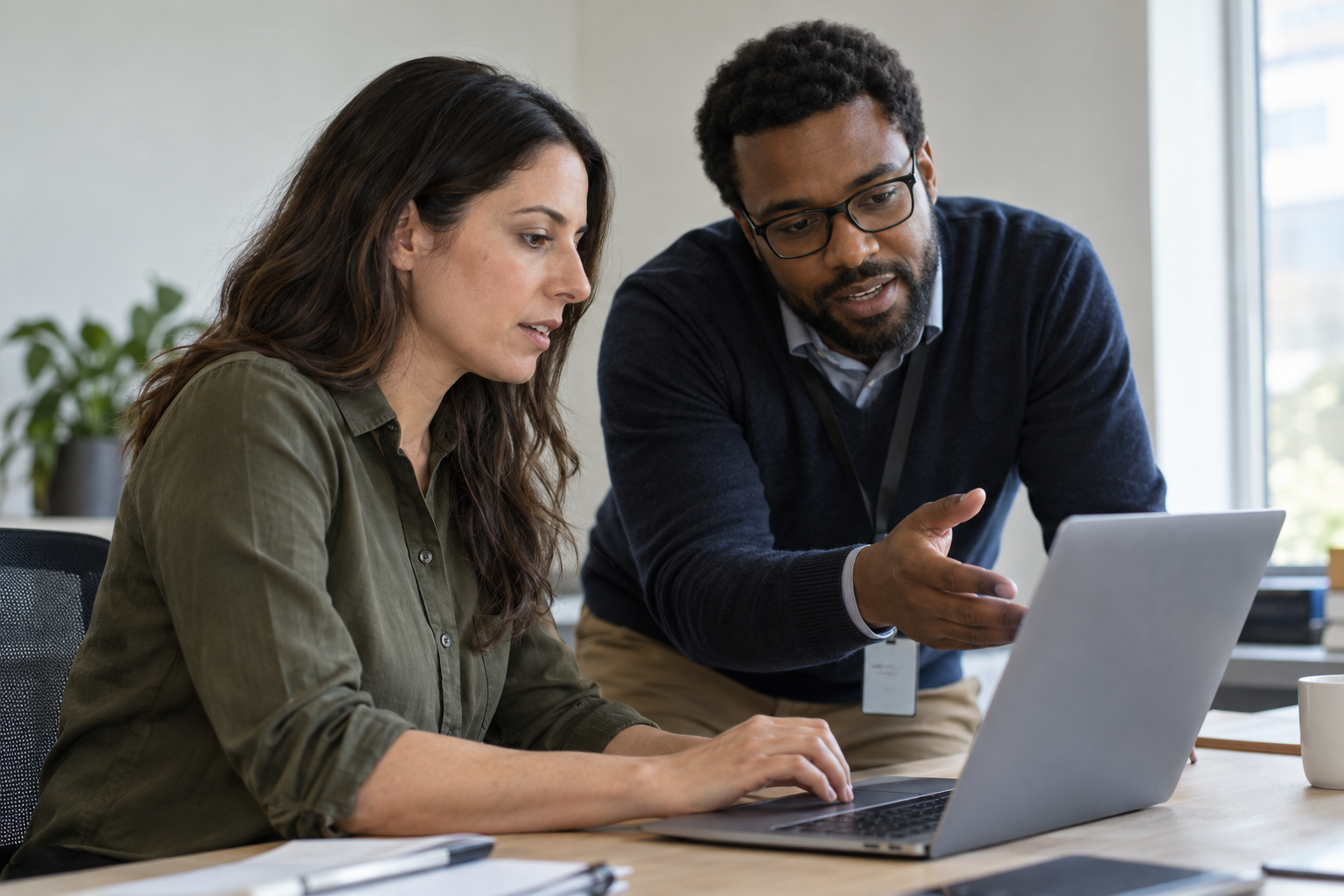 A software evaluator and IT specialist test approval workflow software together on a laptop.