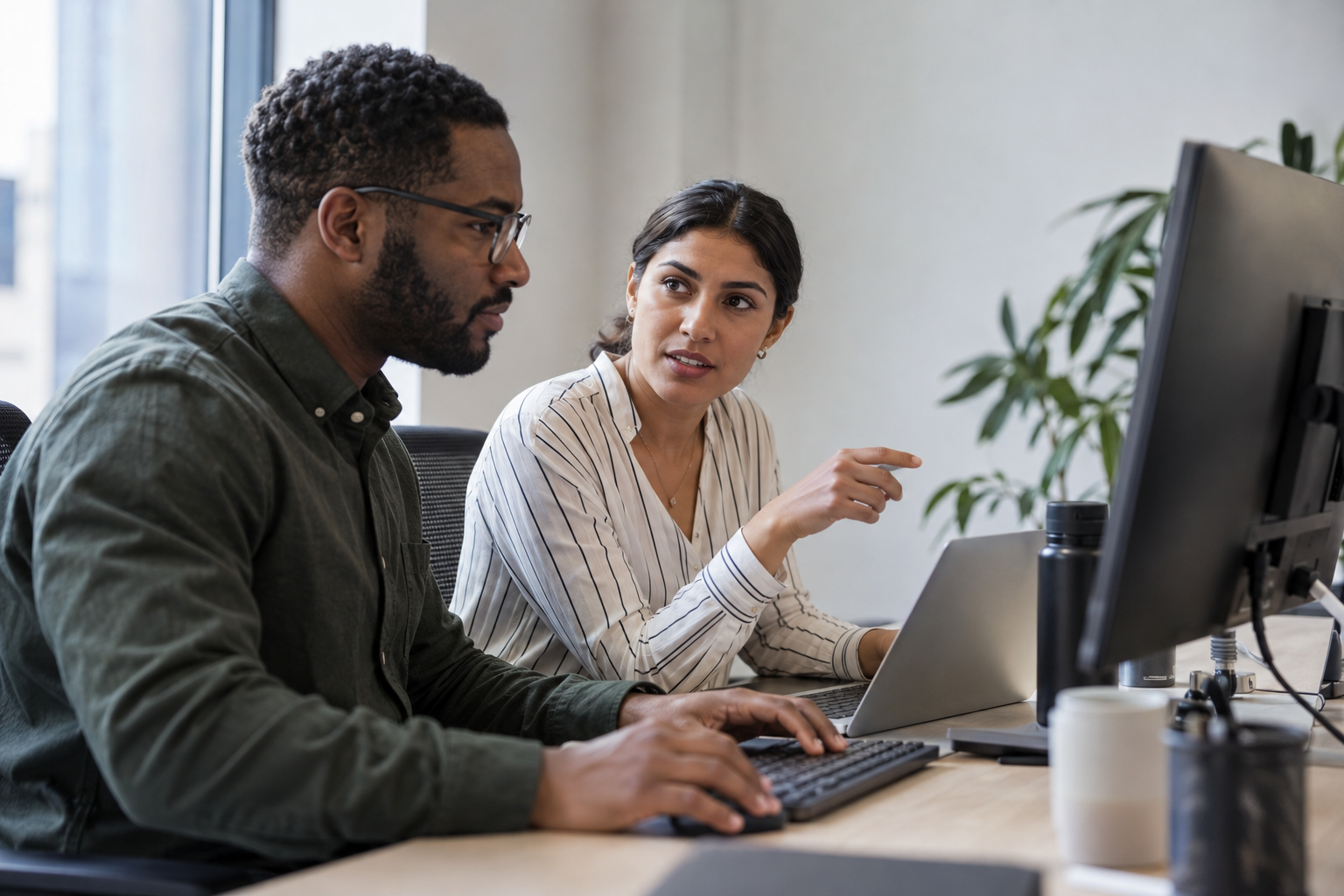 Two operations colleagues compare a routine digital transaction with an exception while working at a desktop and laptop.