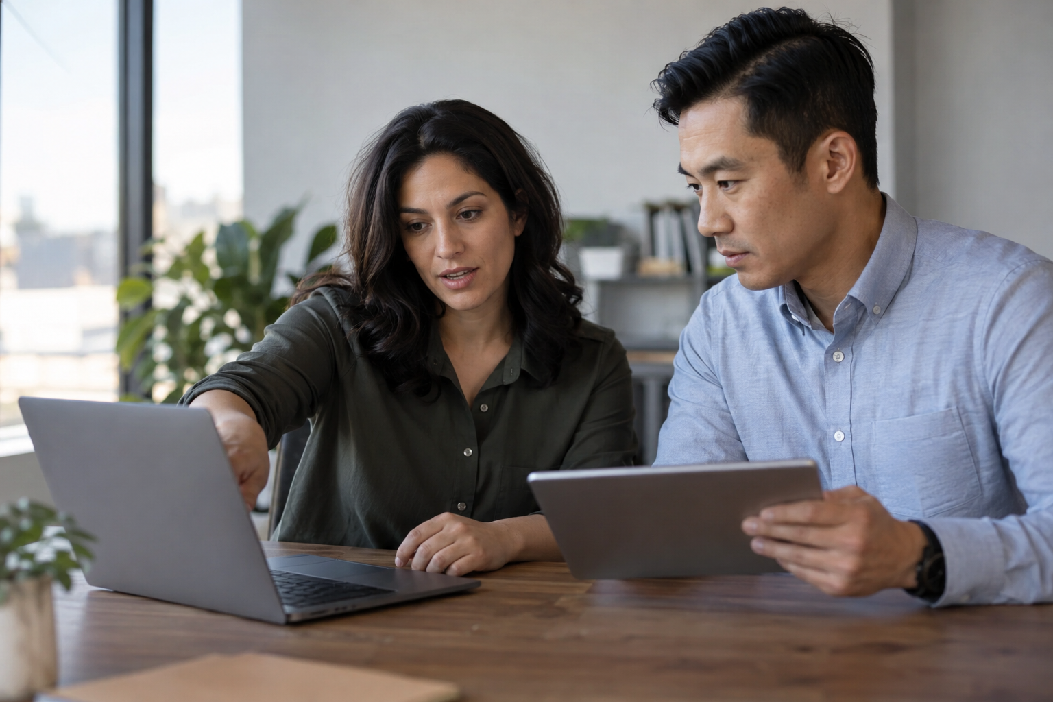 A marketing lead and operations manager evaluate digital approval routing using a laptop and tablet.