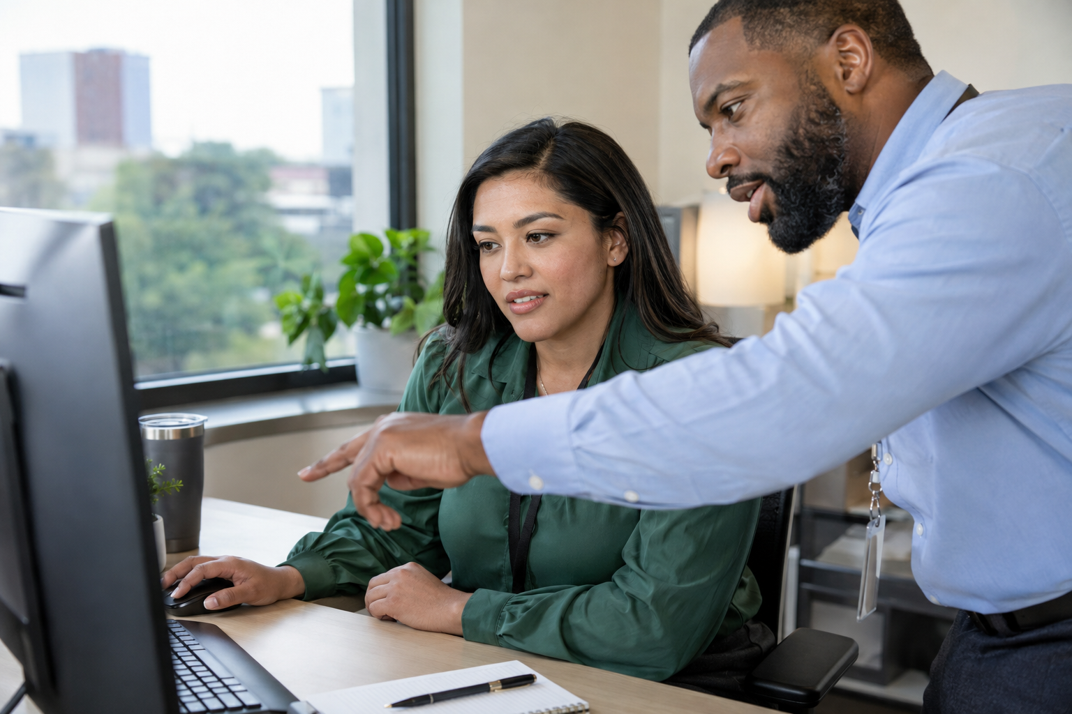 An HR specialist and department supervisor review a digital time-off request and confirm backup approval coverage at a computer.