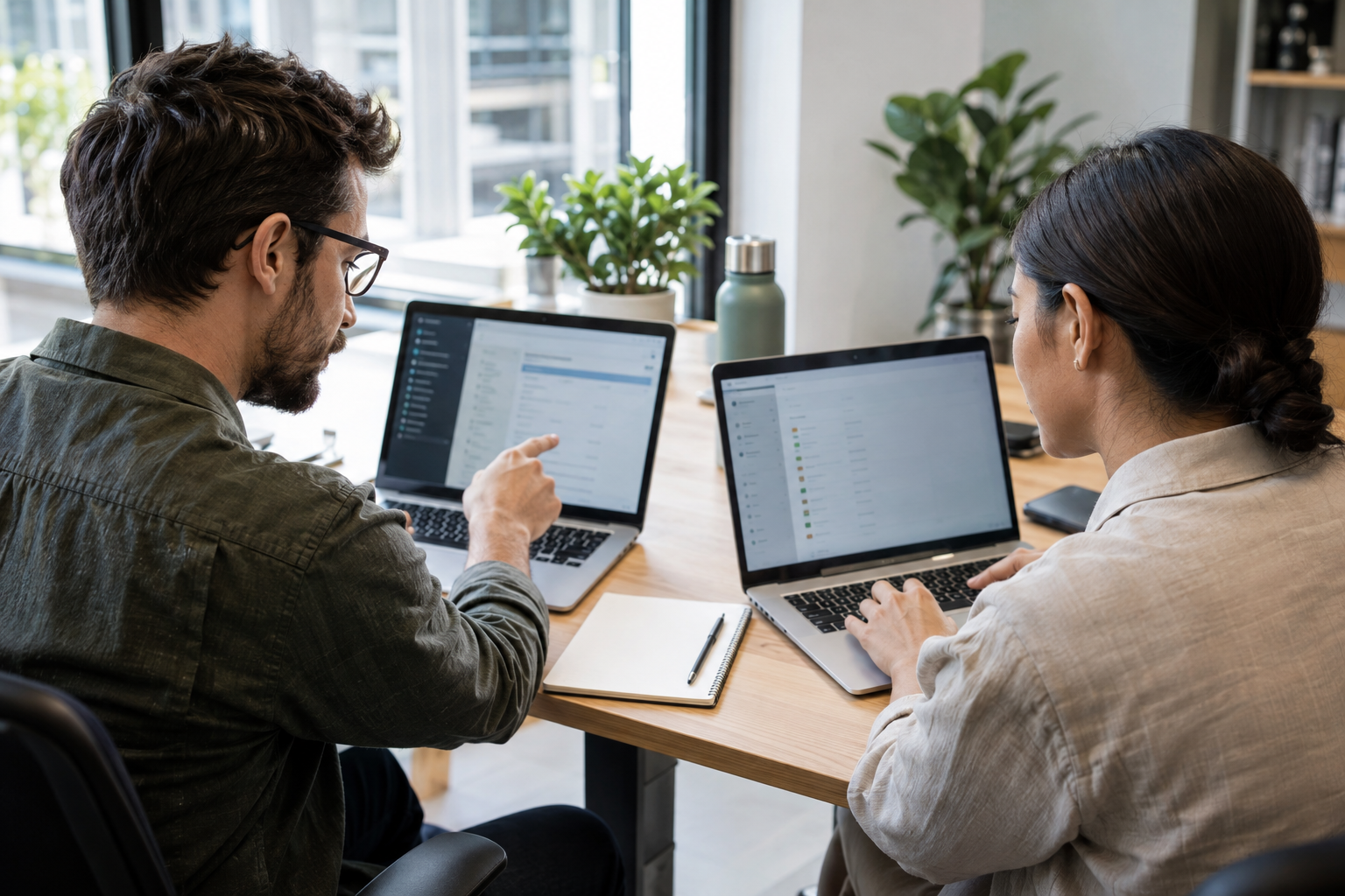 An automation engineer and operations specialist use two laptops to configure and check a scheduled workflow trigger.