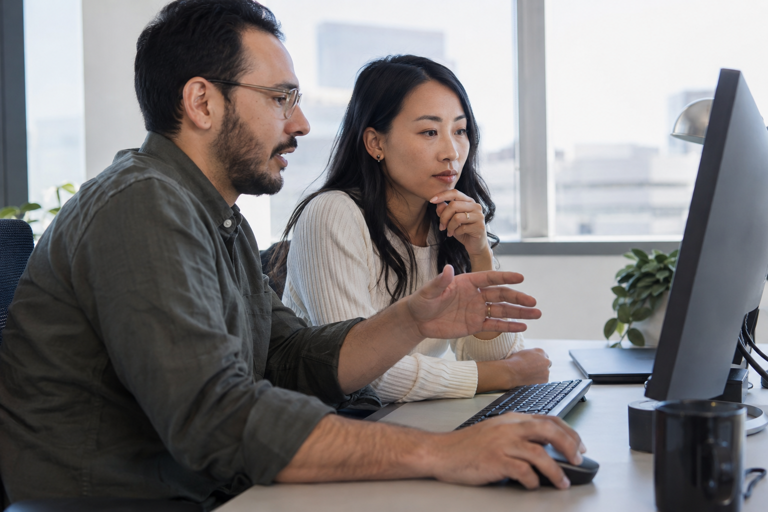 A finance lead and integration engineer assess workflow automation costs together at a desktop computer.