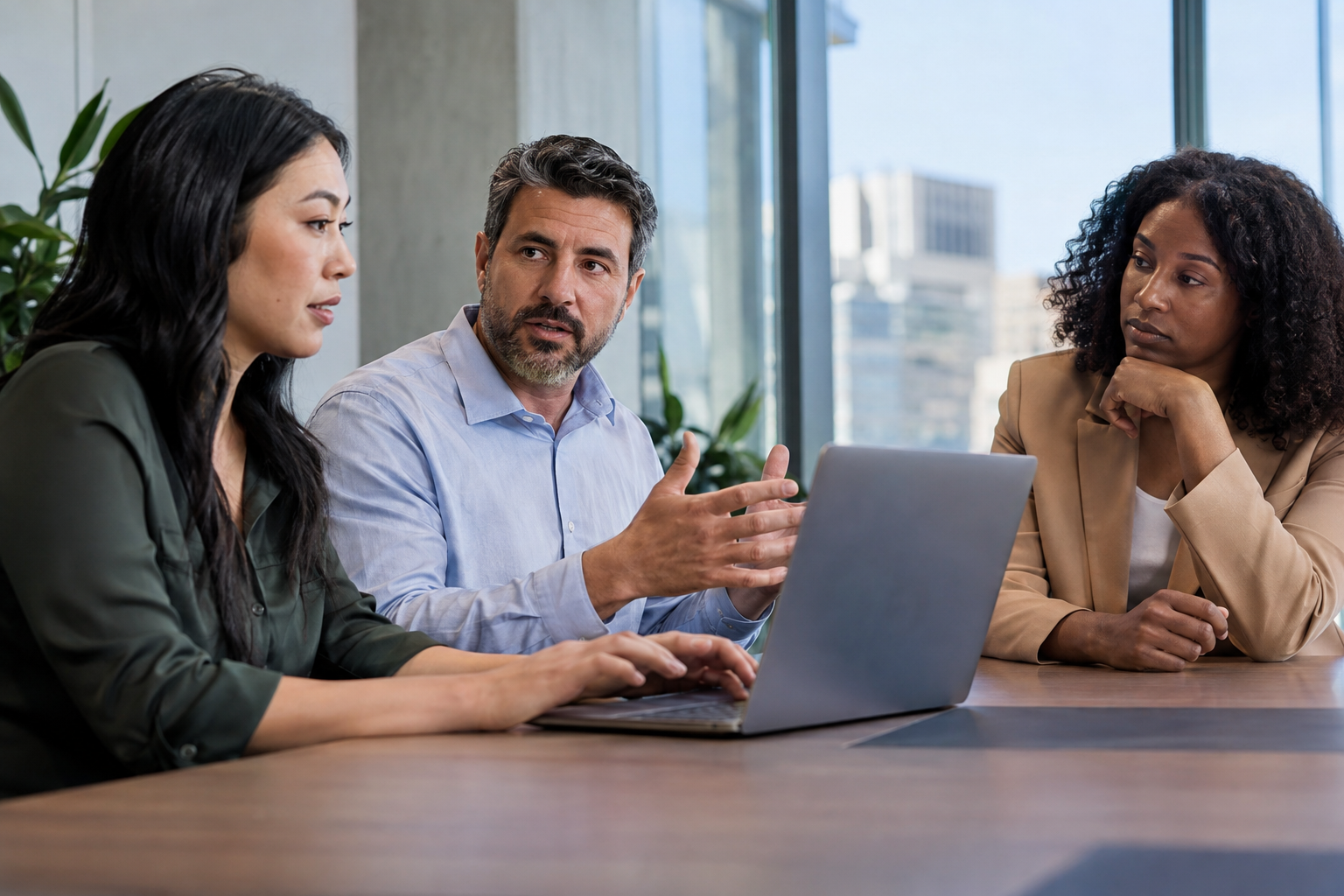 HR systems lead, finance partner and department director review a proposed team restructuring together on a laptop.