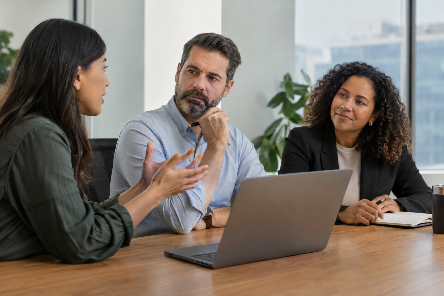 An employee discusses project priorities with her primary manager and a secondary project lead in a working office.