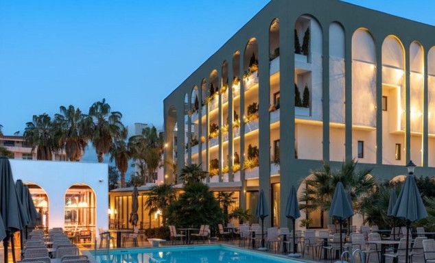 Evening view of the exterior of the hotel with a swimming pool and large seating area
