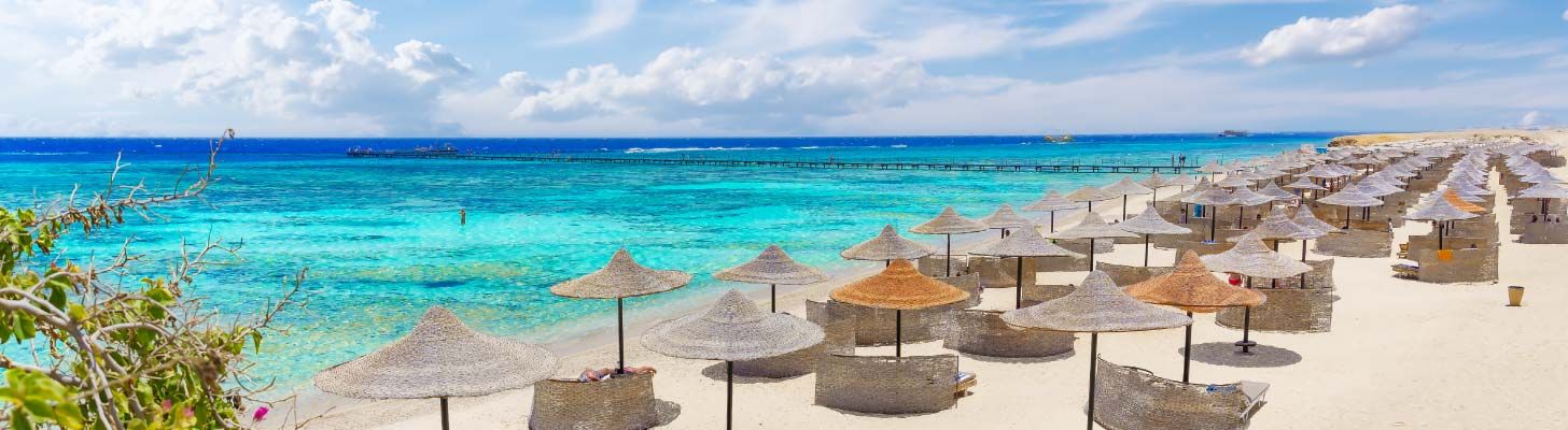 Umbrellas & loungers on sandy beach with turquiose water in Egypt