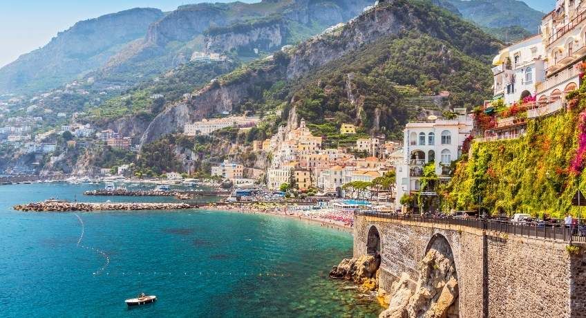 Mountainous backdrop with colourful buildings with a beach and waters