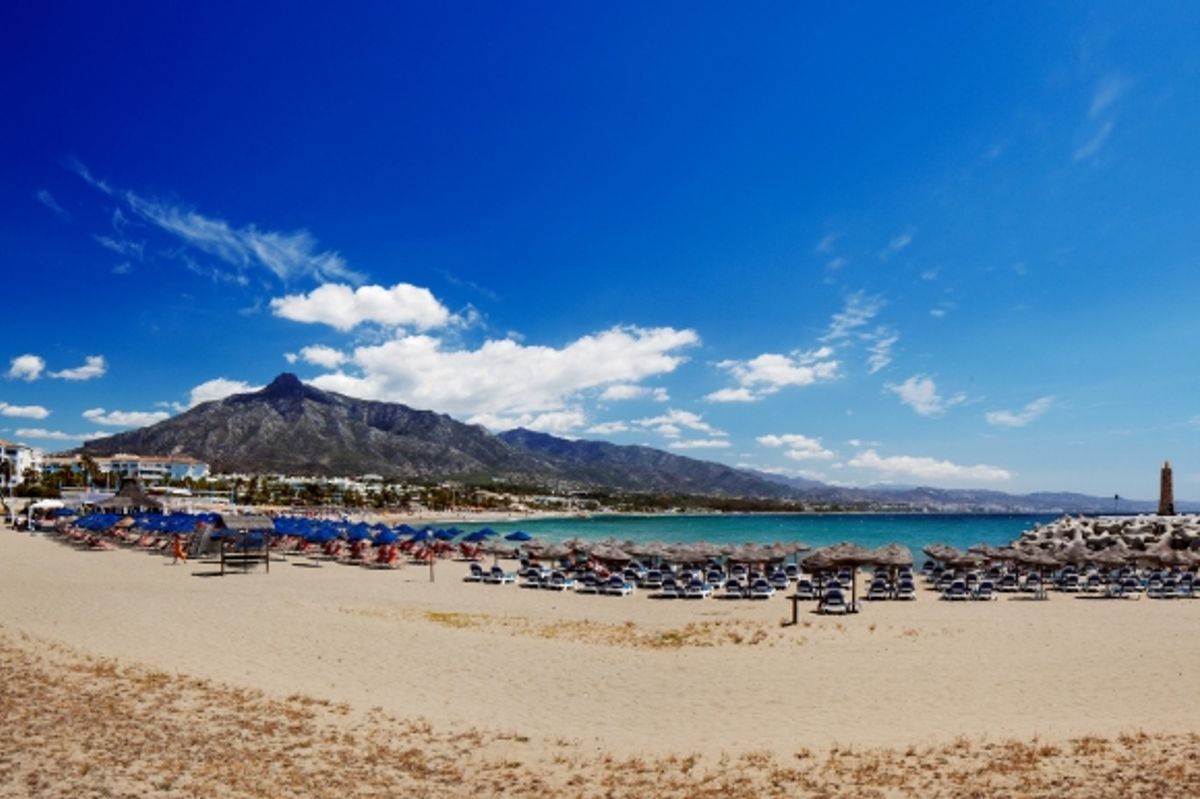 View of the popular Puerto Banus Beach in Marbella scattered with sunloungers.