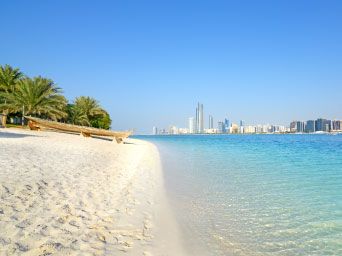 Traditional boat on the beach with Abu Dhabi skyline in the distance