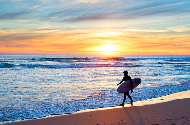 Surfer with board walking along the beach in the sunset, Algarve