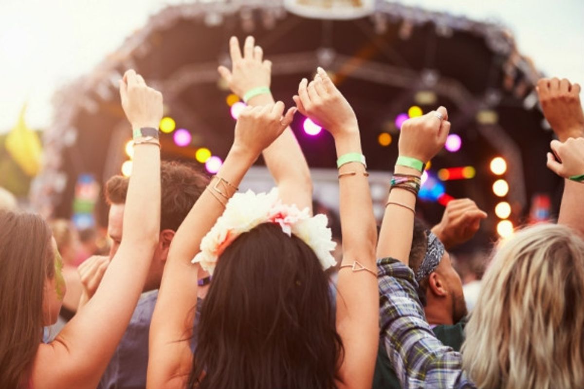 People dancing with their hands in the air in front of the stage at a festival in Spain.
