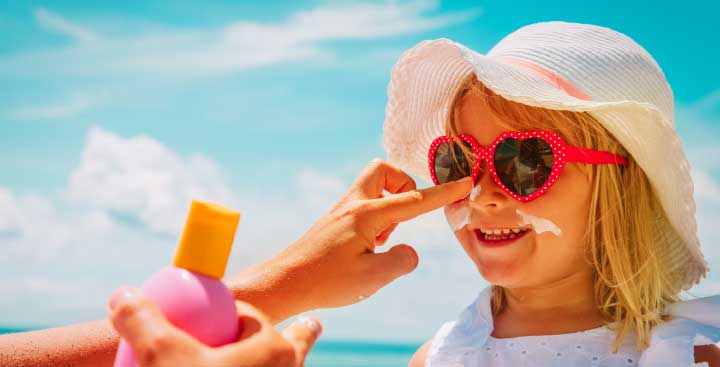 Child having suntan lotion applied