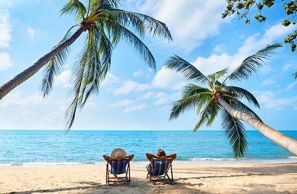2 people sitting on deckchairs on a beach