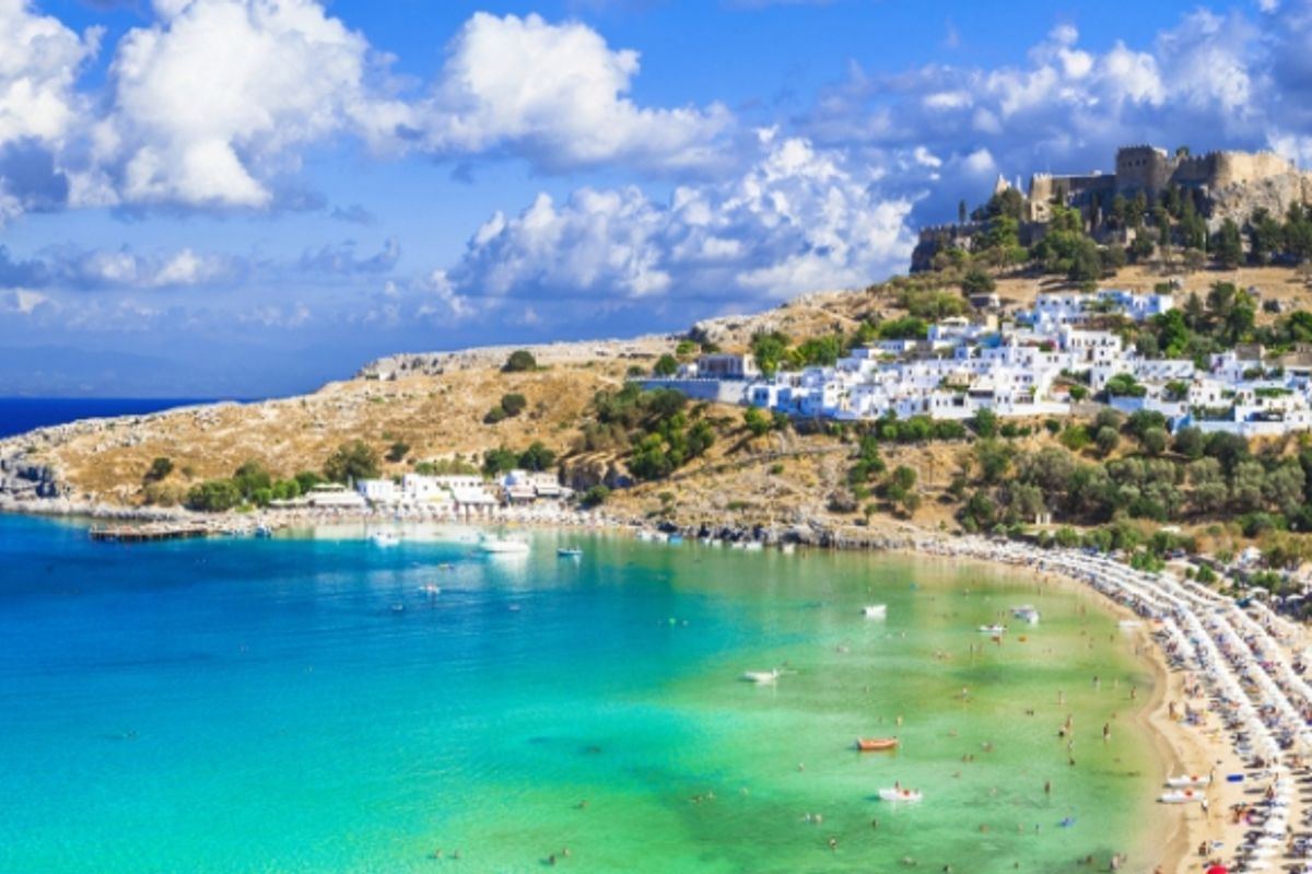 Panoramic view of Lindos shimmering blue bay, village and Acropolis in Rhodes Greece.