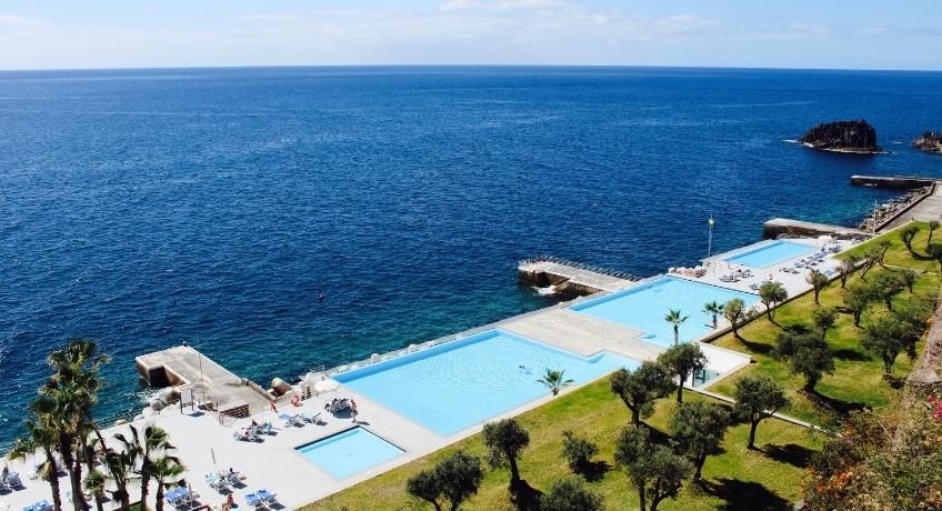3 infinity swimming pools overlooking the ocean with green gardens surrounding
