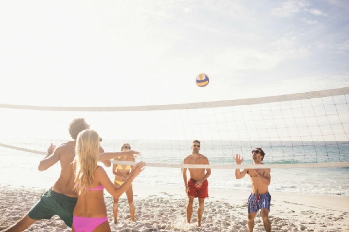 A group of people playing volleyball on the beach.