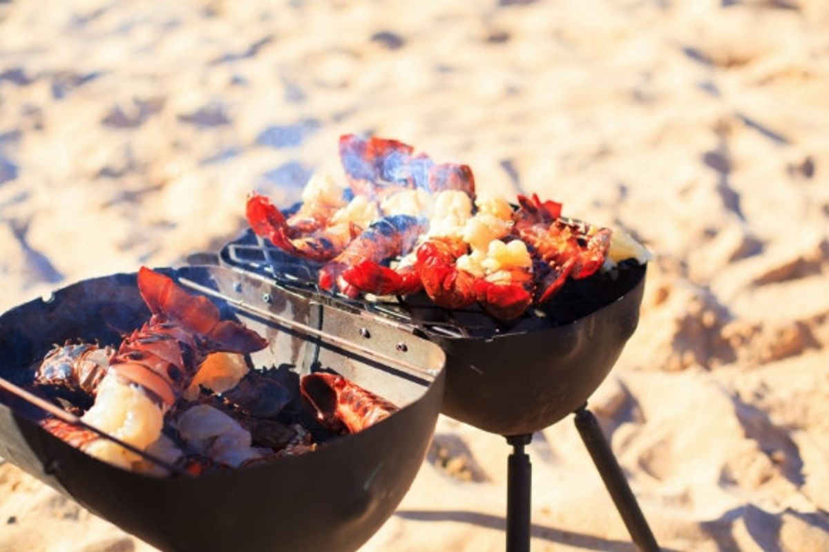 Grilled meats and fish on a smokey barbecue on the beach.
