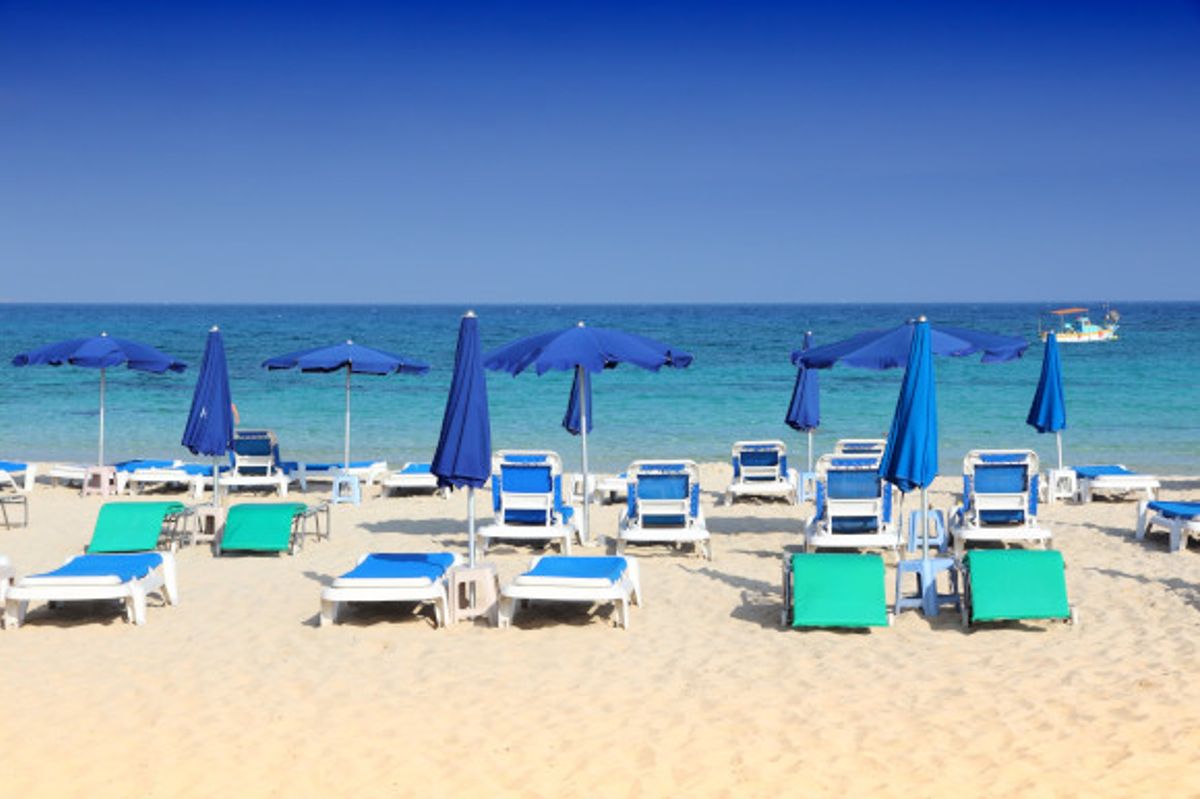 Makronissos Beach in Cyprus with a golden stretch of sand scattered with sunloungers and clear waters providing the backdrop