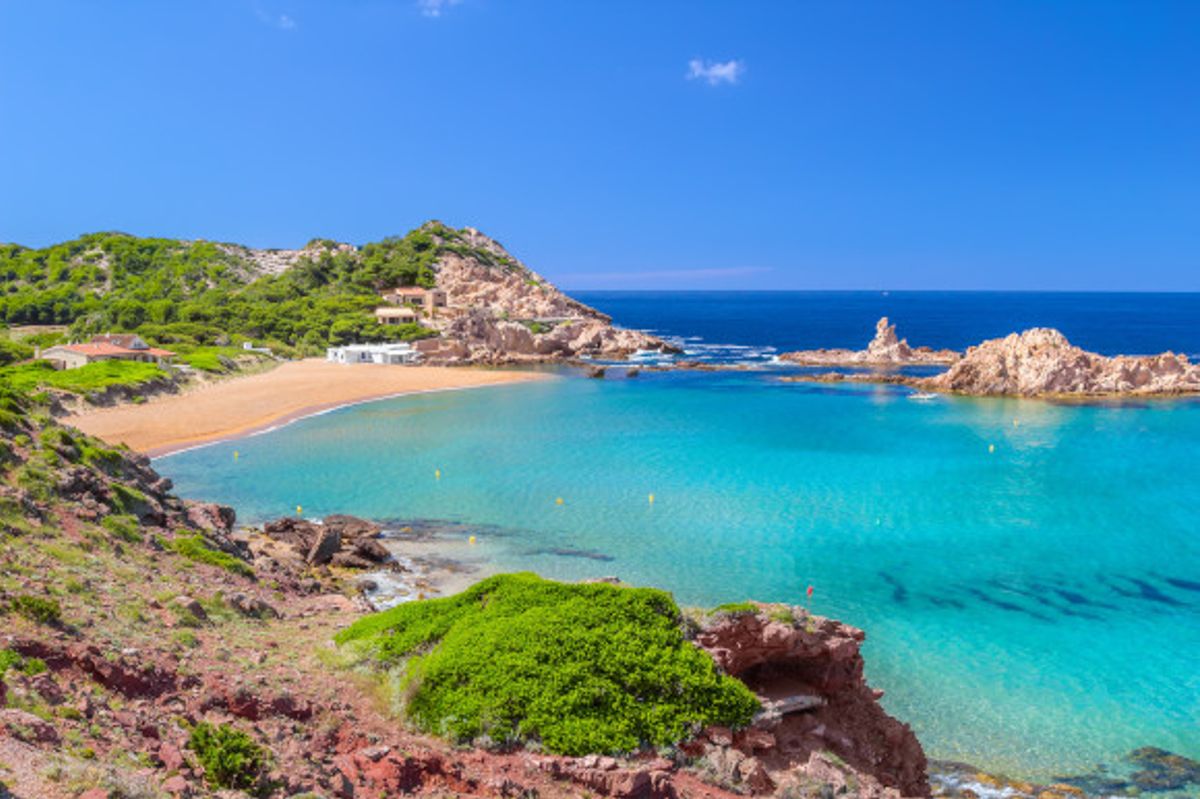 Cala Pregonda Beach on the island of Menorca with shallow blue water and golden sand