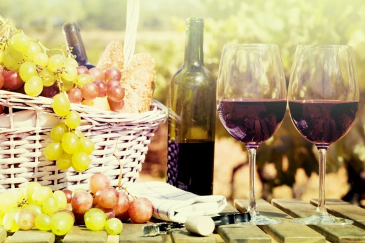 Ripe grapes in a picnic basket and red wine served in a glass from the bottle on a sunny day in Spain.