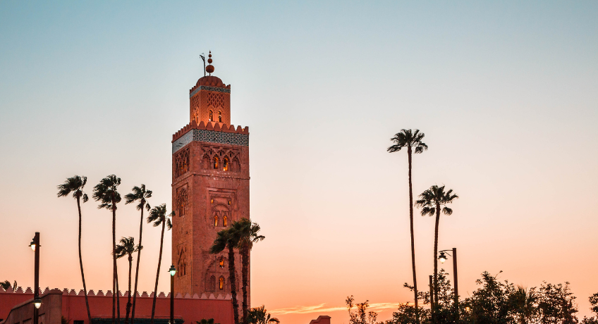 Marrakech mosque tower with palm trees at dusk