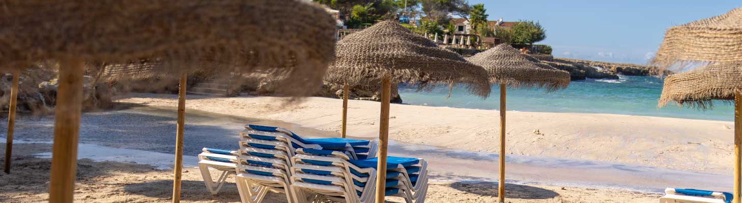 Sun loungers & umbrellas on the beach at Cala Blanca, Menorca