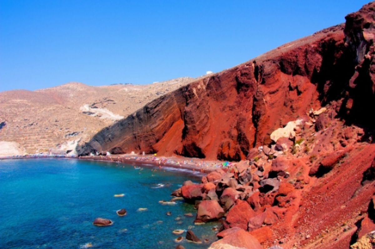 A striking view of the red rocks overlooking the azure water at Santorini's famous Red Beach