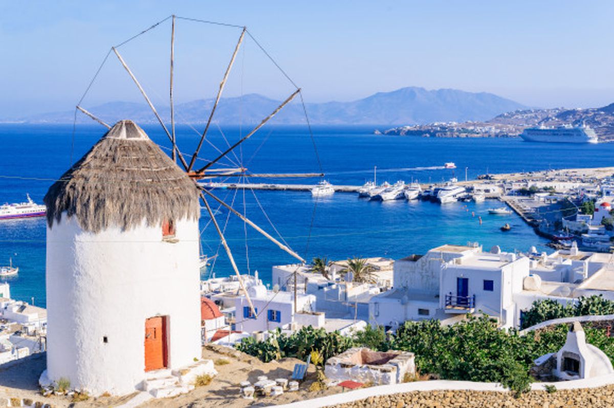 An elevated view of the iconic windmills on the Greek Island of Mykonos with the Aegean Sea in the distance