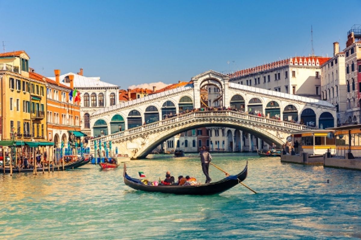 The famous Rialto Bridge in Venice surrounded by buildings with a gondola gliding along the water