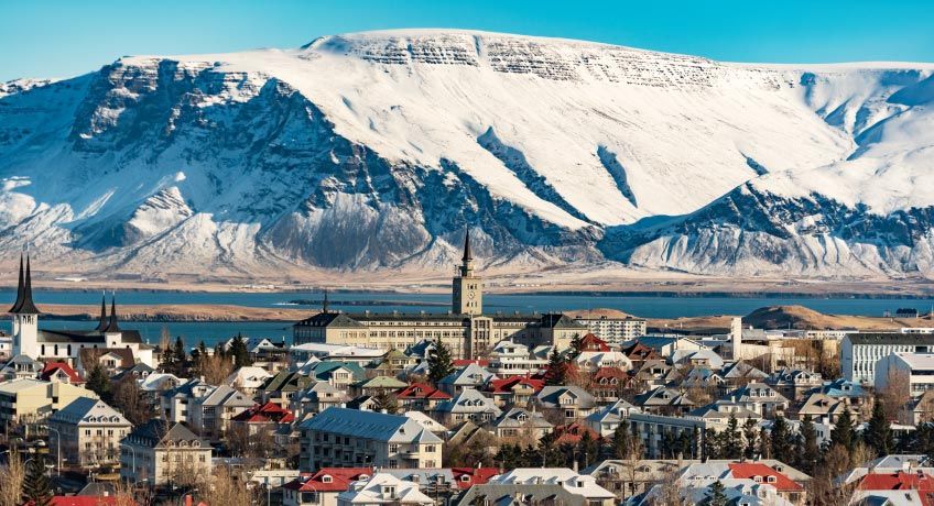 Traditional houses against a snowy mountain backdrop in Reykjavik