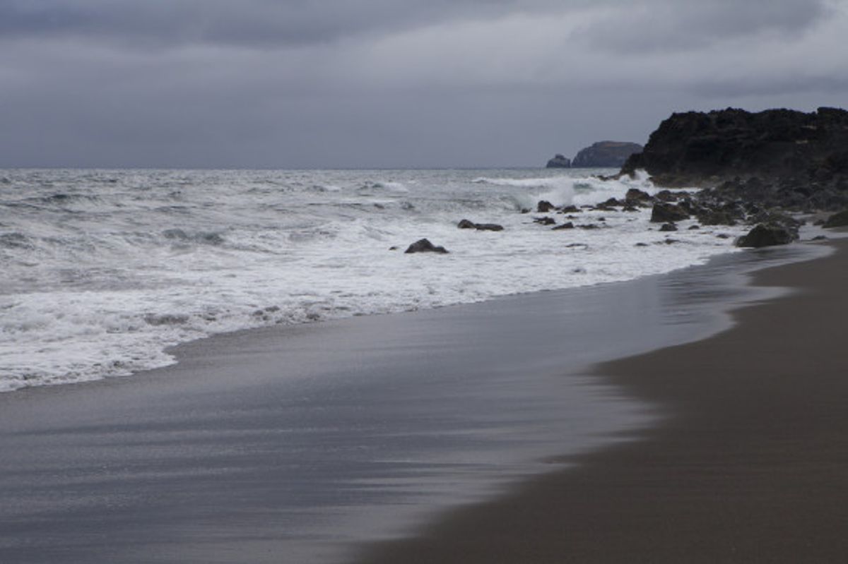 The volcanic, black sands of Praia de Santa Barbara Beach in the Azores region of Portugal