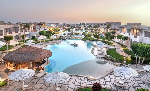 Large outdoor swimming pool surrounded by small villa buildings, a bar area plus waterslides