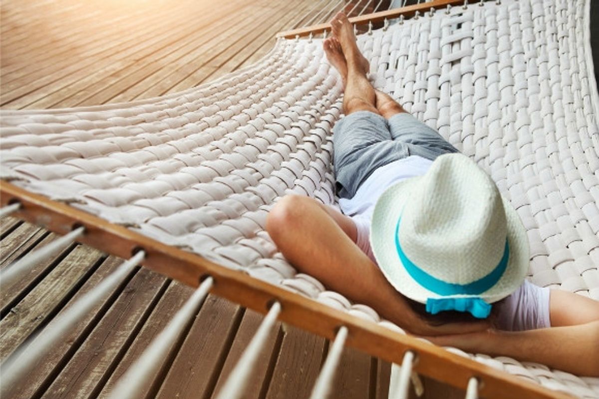 A man having a siesta and relaxing on the beach inside a hammock.