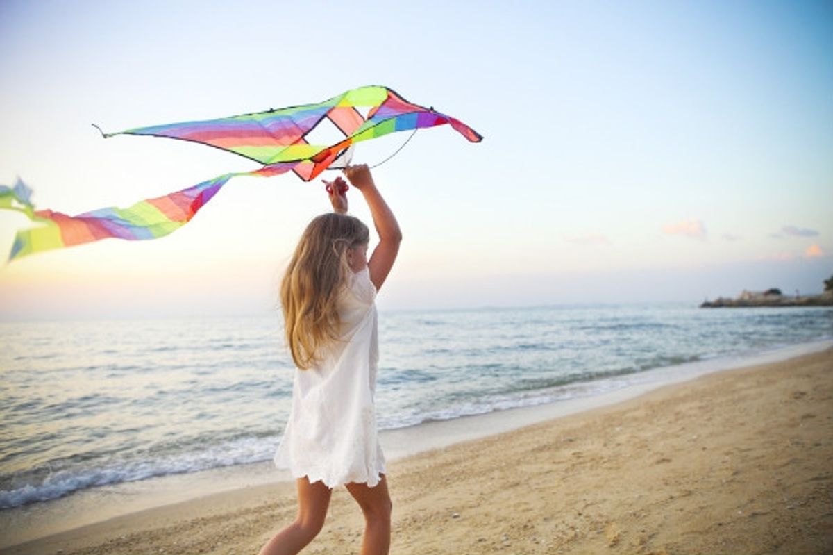 Little girl running and trying to fly a kite on the beach