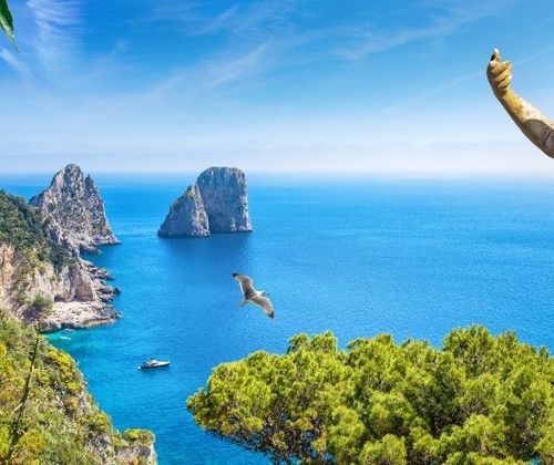 Roman looking statue overlooking rocky cliffs and clear blue waters