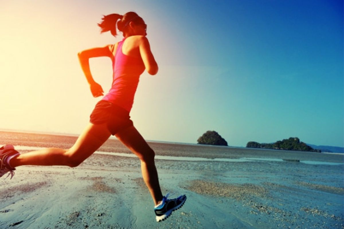 A woman running along the sea front as the sun is rising.