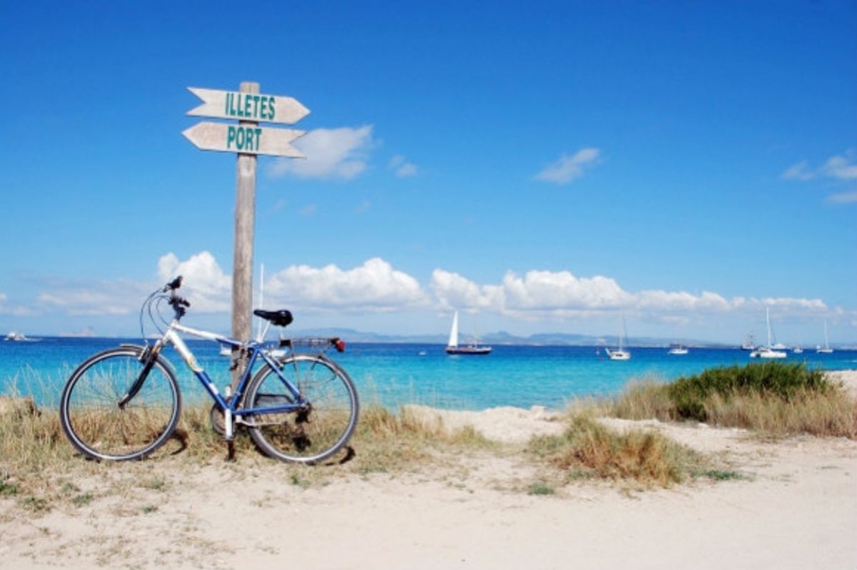Toe-sinking powder white sands of Ses Illetes in Formentera the Balearic Islands and signs to the beach with a bike leaning against them