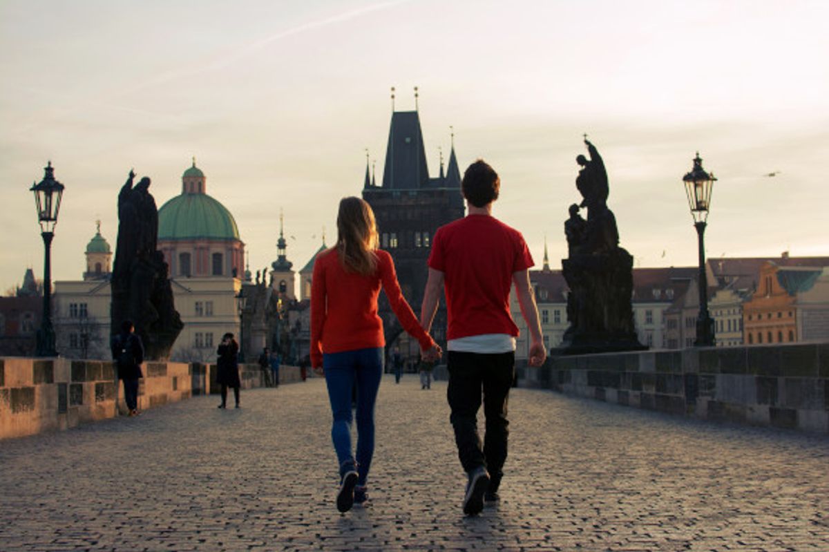 Couple enjoying a romantic stroll over the cobbled Charles Bridge in the city of Prague