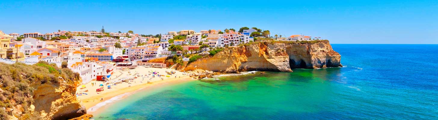 Houses perched on the cliff top overlooking a beach in the Algarve