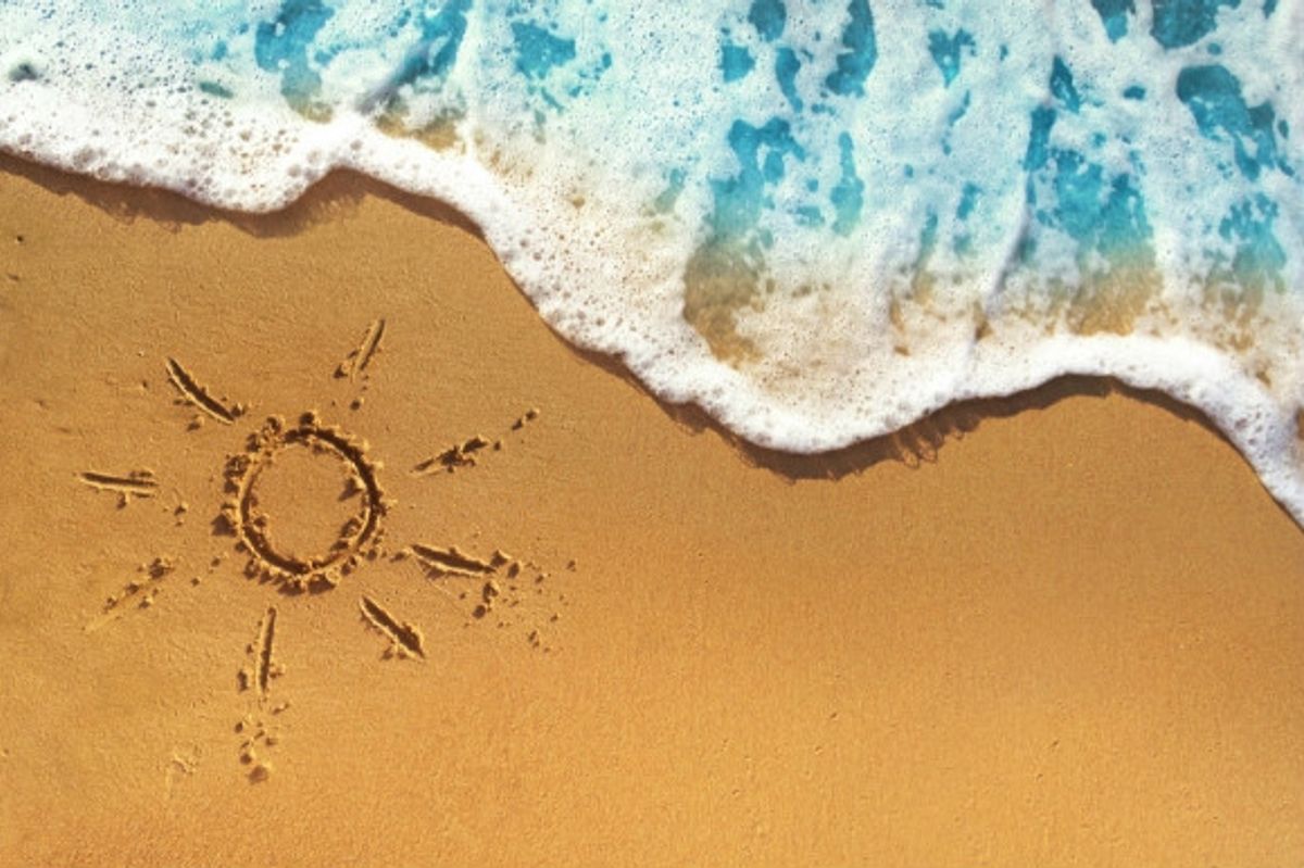 The picture of the sun drawn in the sand as the waves come onto the beach.